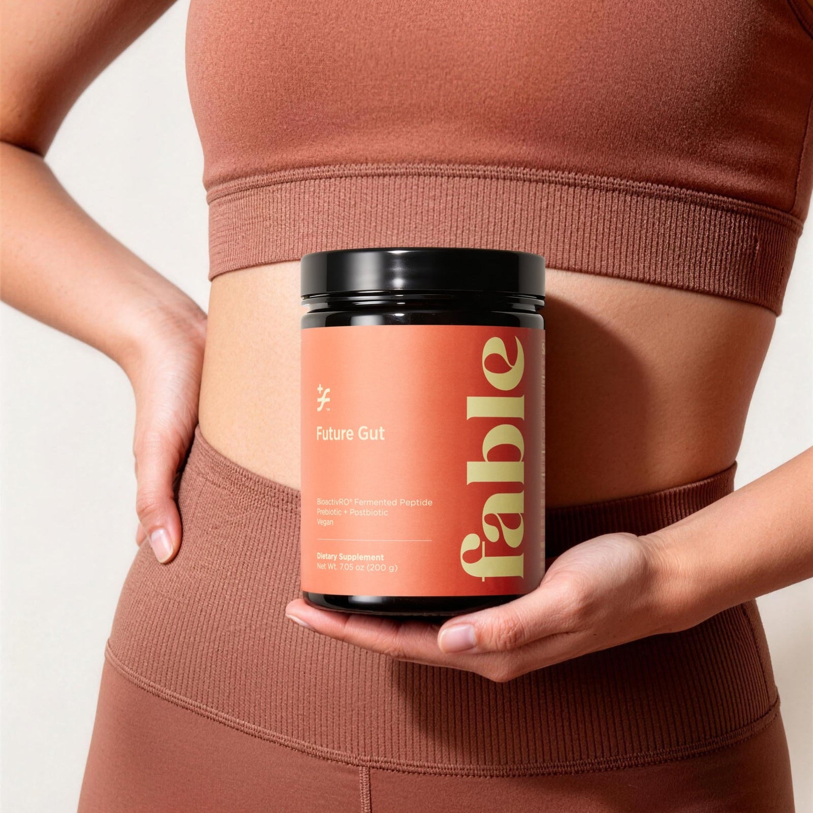 Person wearing a brown athletic outfit holding a container labeled 'fable'.